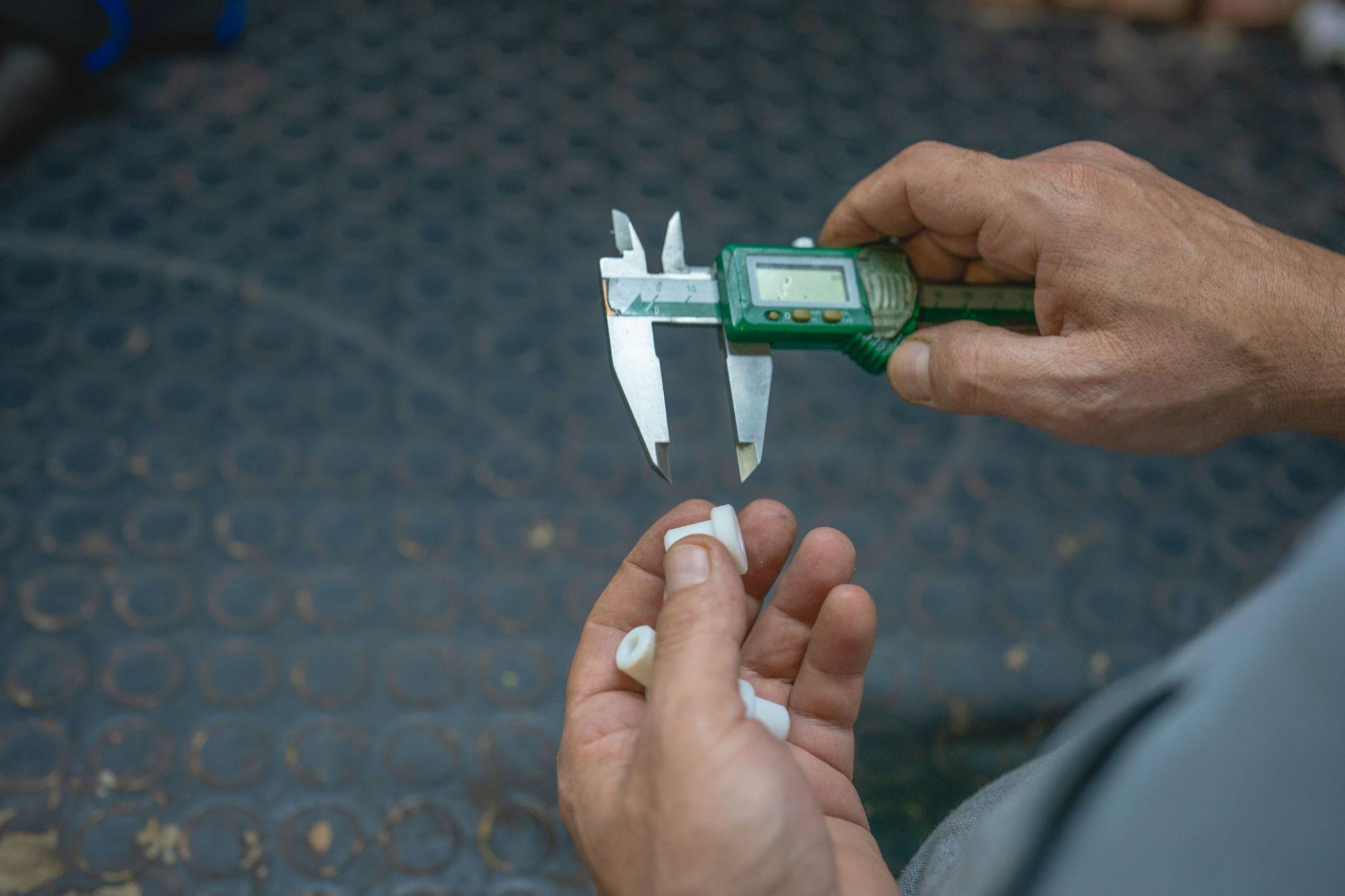 Worker measures plastic part with caliper.
