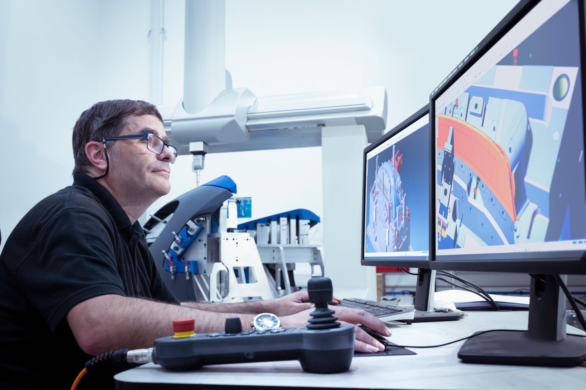 Worker inspecting injection moulded plastic parts in laboratory in automotive parts factory.