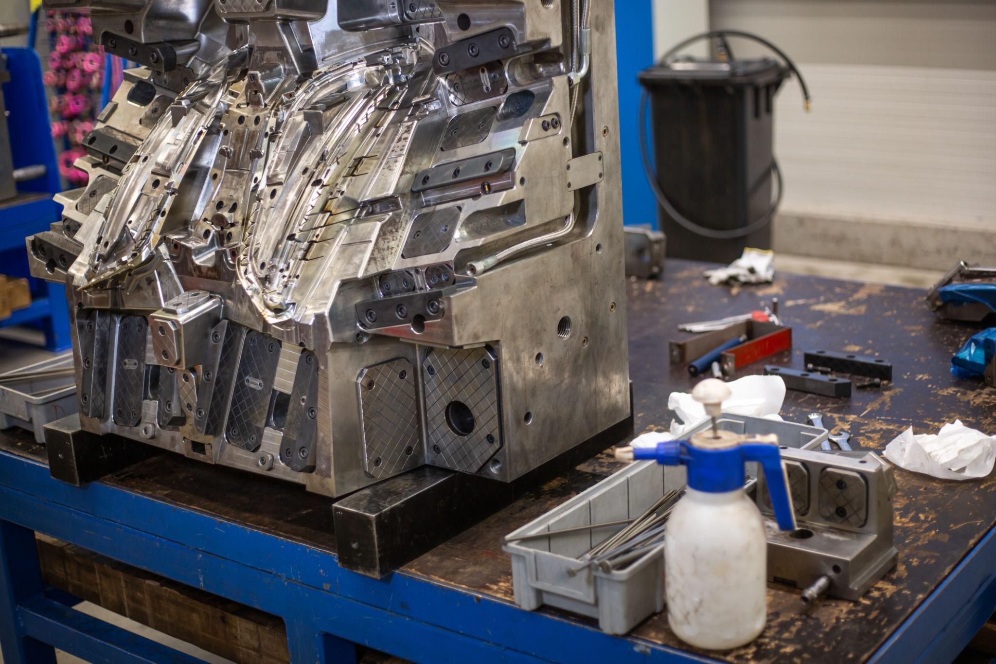 Injection mold under maintenance with huge arrenge of maintenance equipment, industrial concept.