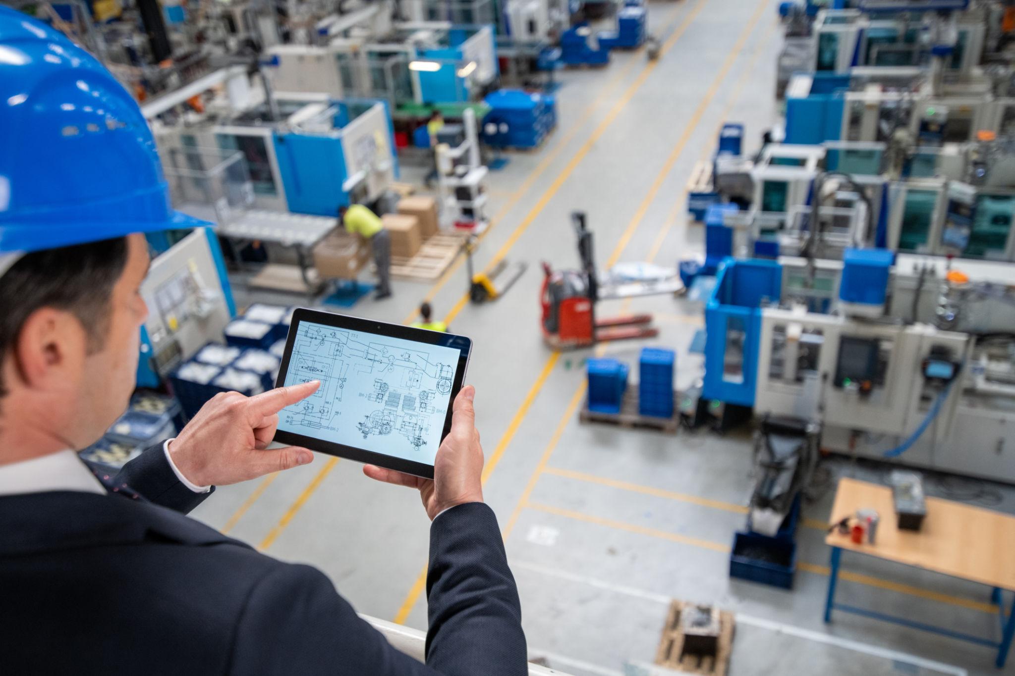 Manager using digital tablet in factory.